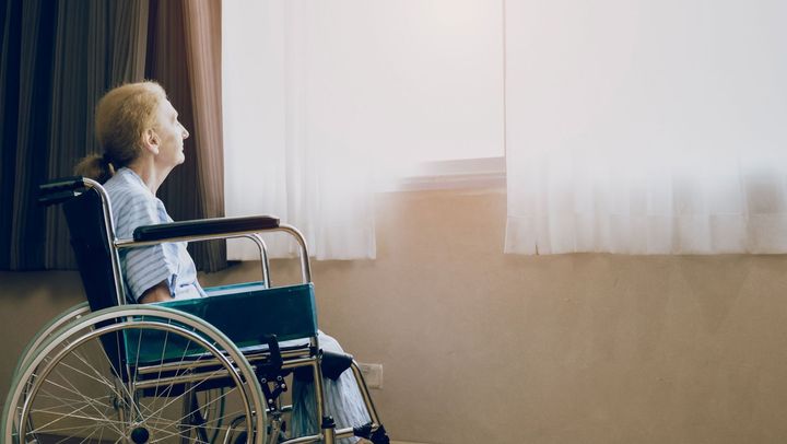 Retirement and Lonely women concept.Panoramic caucasian elderly woman in wheelchair while looking out the window in nursing home or hospital.