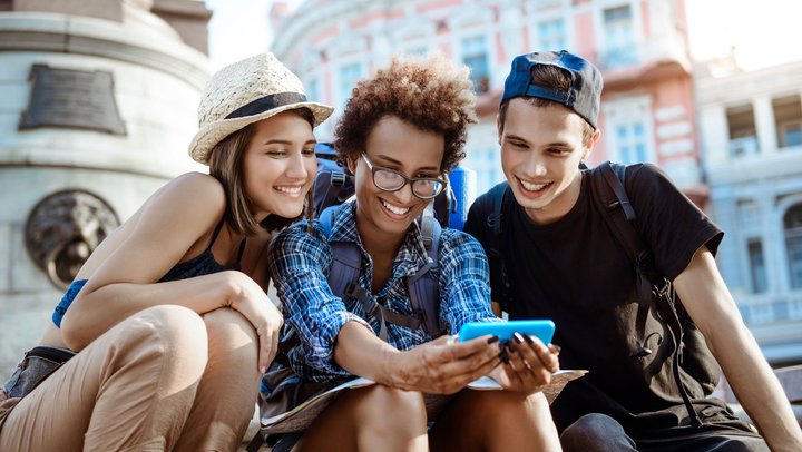 Friends travelers with backpacks smiling, making selfie, sitting near sight.